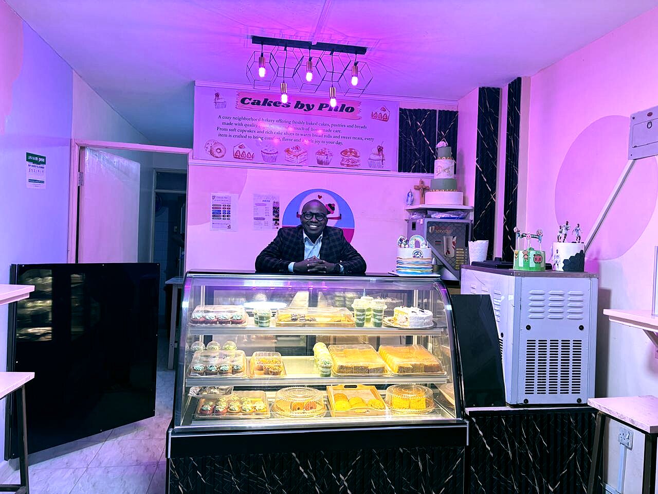 Phlo standing behind the Cakes by Phlo display case