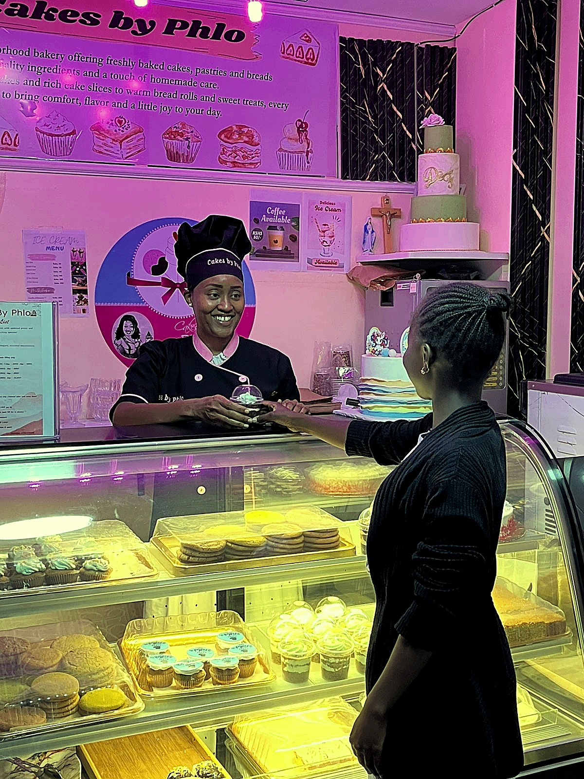 Phlo handing a fresh dessert to a customer at the Cakes by Phlo counter