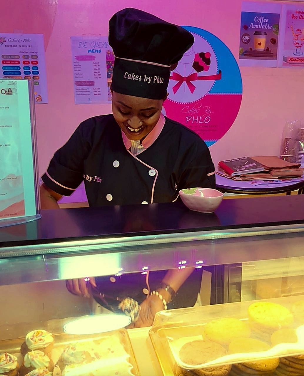Phlo smiling while plating fresh treats behind the counter